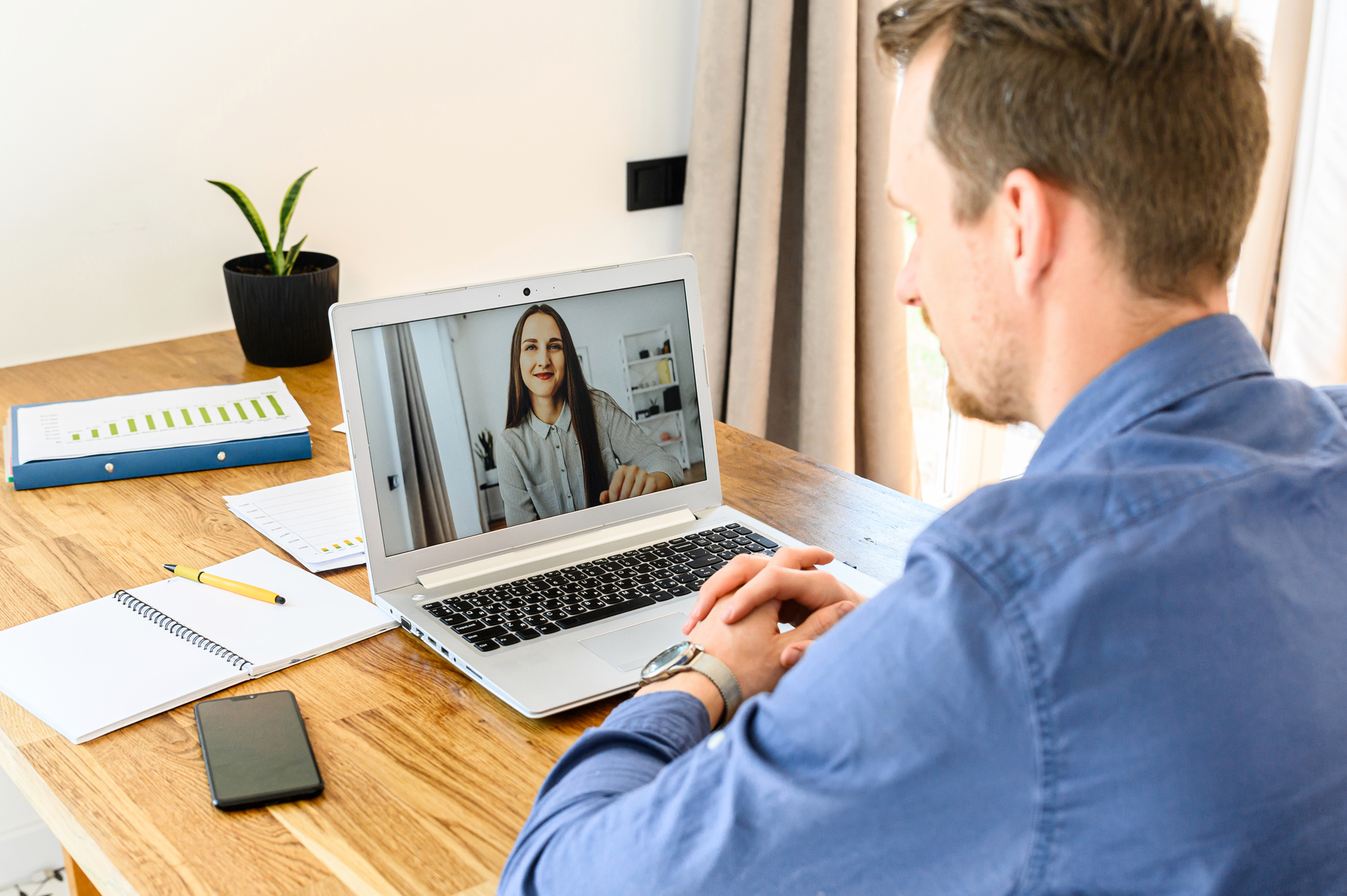 Man sitting at desk on video conference with woman