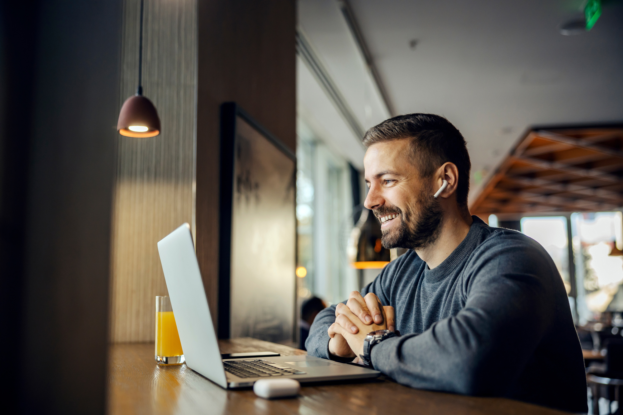 Man in coffee shop smiling at video call